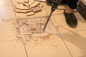 Tiler are removing broken tiles for repair.